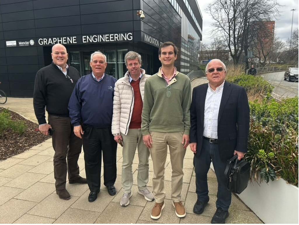 Five men standing outdoors on a pathway, posing for a group photo.
